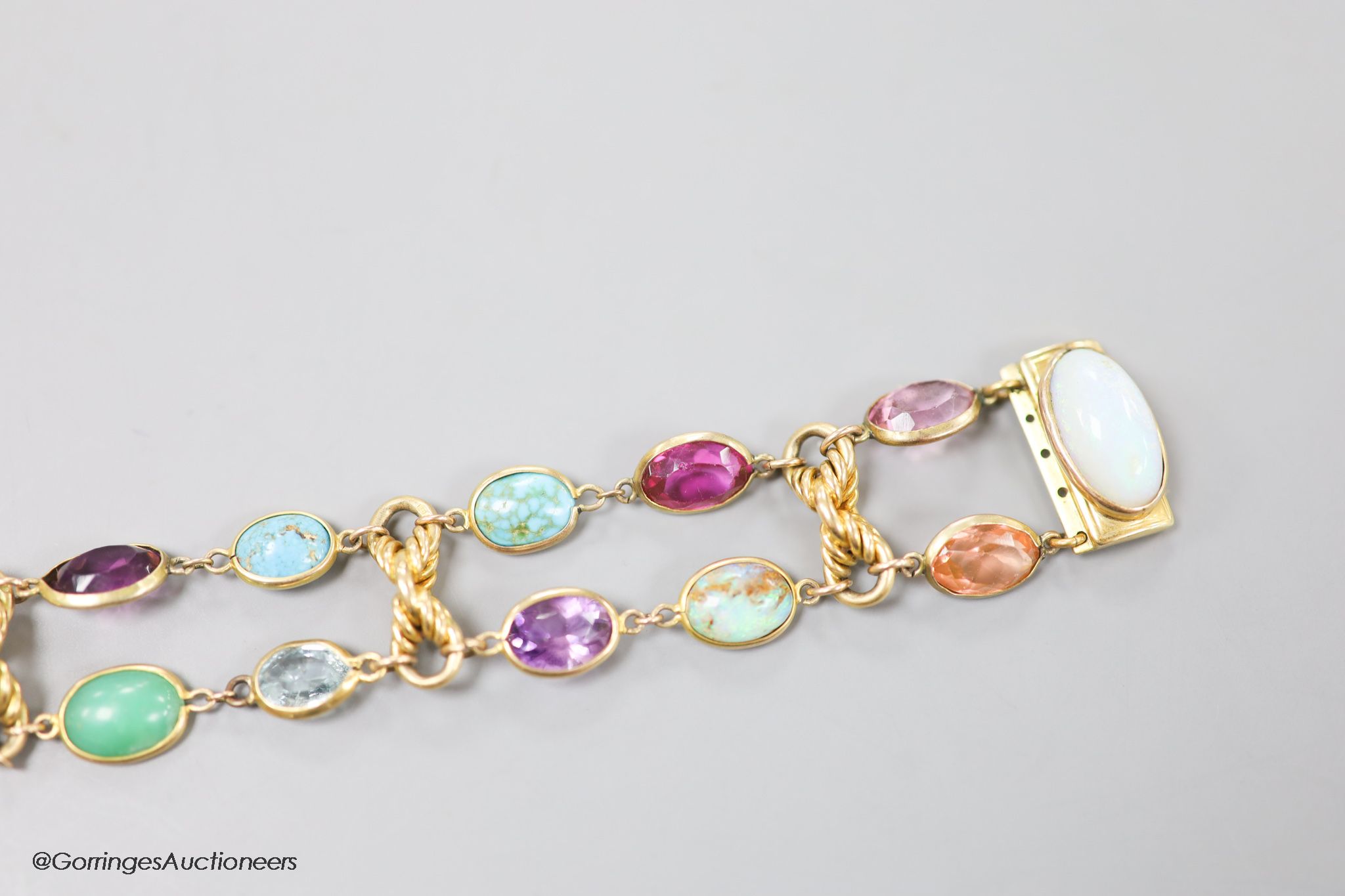 An early 20th century yellow metal and multi gem set bracelet, including white opal, turquoise, amethyst etc, 17cm, gross weight 30.3 grams.